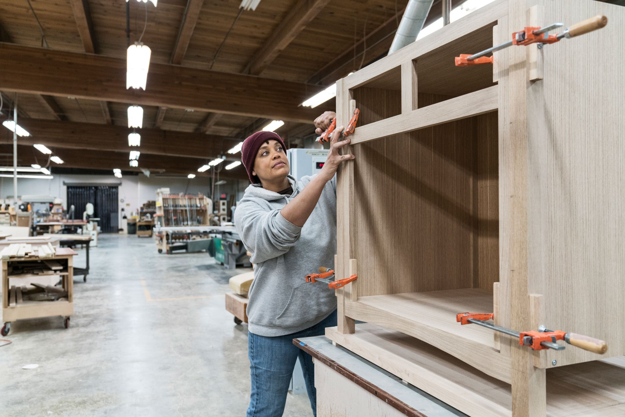 Female carpenter using tools in a woodworking workshop.